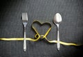 Fork and spoon with heart shape made from yellow ribbon on black Royalty Free Stock Photo