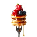 A fork with a stack of mini pancakes drizzled with syrup and topped with berries creates a delicious breakfast close-up. Royalty Free Stock Photo