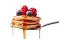 A fork with a stack of mini pancakes drizzled with syrup and topped with berries creates a delicious breakfast close-up. Royalty Free Stock Photo