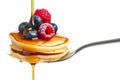 A fork with a stack of mini pancakes drizzled with syrup and topped with berries creates a delicious breakfast close-up. Royalty Free Stock Photo