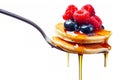 A fork with a stack of mini pancakes drizzled with syrup and topped with berries creates a delicious breakfast close-up. Royalty Free Stock Photo