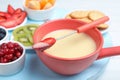 Fork with strawberry dipped into white chocolate fondue and ceramic pot Royalty Free Stock Photo