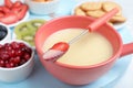 Fork with strawberry dipped into white chocolate fondue and ceramic pot Royalty Free Stock Photo
