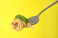 Fork with tasty pasta, basil and tomato sauce on yellow background, closeup Royalty Free Stock Photo