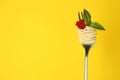 Fork with tasty pasta, tomato sauce and basil leaves on yellow background, space for text Royalty Free Stock Photo