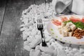 Fork, wineglass and plate of ham, walnuts and cheese on white rocks. Close-up of healthy snacks on a wooden background. Royalty Free Stock Photo