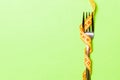 Fork wrapped in measuring tape on green background. Top view of overeating concept