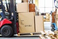 Forklif with a three large cardboard boxes in a modern warehous