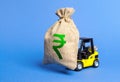 Forklift carries a huge money bag with the symbol of the Indian rupee. Budget and corruption, investment and economic growth.