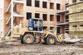 A forklift at a construction site is lifting a reinforced concrete slab. Construction machine. Construction of a brick building