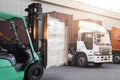 Forklift Driver Loading Package Boxes. Trailer Trucks Parked Loading at Dock Warehouse. Shipment Delivery Service.