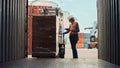 Forklift Driver Loading a Shipping Cargo Container with a Full Pallet with Boxes in Logistics Port