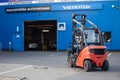 Forklift driving in front of garage warehouse
