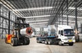 Forklift lifts heavy steel coil inside a warehouse at a seaport-bounded area to load onto truck. Raw material handling.