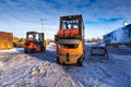 Forklift loaders for warehouse are waiting work outdoors during frosty day in the cargo center. Pallet stacker trucks in