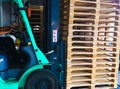 Forklift operator handling wooden pallets in warehouse cargo for transportation to customer factory