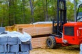 Forklift is putting outdoors at loader palette home framing beams for house under construction