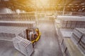 A forklift truck drives through a huge warehouse with stacks of vacuum-packed water or beer packages on pallets. View from above.