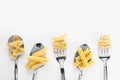 Forks and spoons with various tasty pasta on white background, flat lay. Space for text Royalty Free Stock Photo