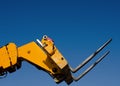 Forks of the Telescopic Forklift Telehandler raised on the blue sky background Royalty Free Stock Photo