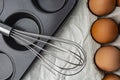 Form for baking cupcakes, eggs in a box and a whisk on a white background, top view Royalty Free Stock Photo