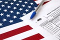 Form 990 Return of organization exempt from income tax and blue pen on United States flag. Internal revenue service tax form