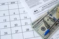 Form W-4 Employee`s withholding allowance certificate and blue pen with dollar bills lies on office calendar. Internal revenue