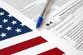 Form W-4 Employee`s withholding allowance certificate and blue pen on United States flag. Internal revenue service tax form