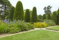 Formal english garden with conifer trees, flowerbeds