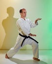 Formal exercises on a colored background with yellow and green tints being performed by a man with a black belt Royalty Free Stock Photo