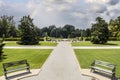 Formal garden with straight paths and benches and a fountain and beautiful trees under cloudy sky with rainbow Royalty Free Stock Photo