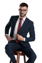Formal man sitting and fixing jacket with style
