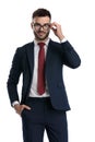 Formal man standing with hand in pocket and fixing glasses Royalty Free Stock Photo