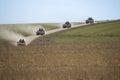 Formation of four tanks driving across a green hill
