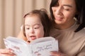 Formation of the skills of a child with down syndrome, girl with her mother and a book at home read Royalty Free Stock Photo