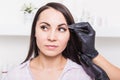 Beautician plucks a young woman`s eyebrows with tweezers