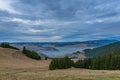 Forming fog over small village in the valley at sunset, view from the top of the mountain, dramatic sky Royalty Free Stock Photo