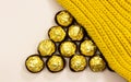 Forming triangle shape from golden premium chocolate sweets under woolen winter scarf