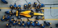 Formula 1 pit crew in blue uniforms surrounds a yellow racing car, performing a pit stop with precision and speed. Royalty Free Stock Photo
