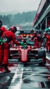 A formula racecar receiving maintenance during a pitstop in wet conditions, highlighting the challenge of racing.