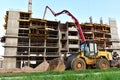 Formworks and pouring concrete through a oncrete pump truck connected to a ready-mixed truck. Wheel loader at construction site.