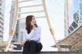 Fornt view of beautiful young Asian woman sitting and talking on phone at urban city background. Royalty Free Stock Photo