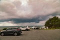 Forster NSW Australia - 13 April 2022: Visitors cars parked at the Bennett`s Head Lookout with dark storm clouds in the distance