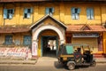 The exterior facade of an old rustic heritage building with yellow walls and a rickshaw