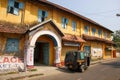 The exterior facade of an old rustic heritage building with yellow walls and a rickshaw