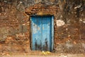 A rustic blue wooden door in an old, ruined laterite brick wall in the heritage town of Royalty Free Stock Photo