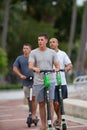 Young men riding rental scooters on Las Olas Riverwalk Royalty Free Stock Photo