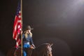 Cowgirl holding America flag in the Stockyards Championship Rodeo