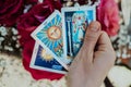 Fortune teller holding oracle cards in hand on flowers background. Tarot reader. Future prediction, esoteric, intuition Royalty Free Stock Photo