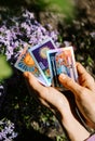 May, 2022 - Kyiv, Ukraine. Fortune teller holding oracle cards in hand on flowers background. Tarot reader. Future Royalty Free Stock Photo